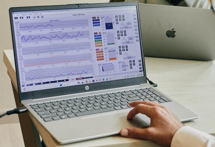 Clinician monitoring real-time neurofeedback brainwave data on a laptop during a training session